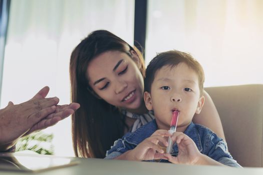 A boy who is taking medication with a fever syringe while going to the doctor.