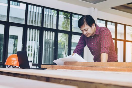 Two engineers are working on a blueprint. With work space