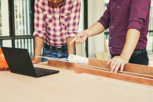 Two engineers are working on a blueprint. With work space