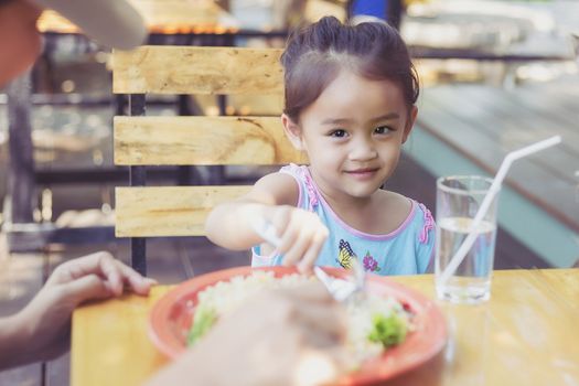 Close up Thai children eating in restaurant with her mother