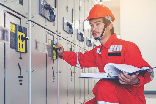 A handsome electrician is checking the electrical equipment to prepare it for use.