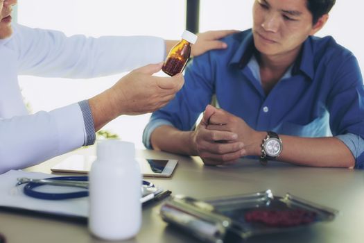 The doctor is explaining something about the medicine to the patient, in order to understand how to use it and to know the benefits and penalties of the drug.