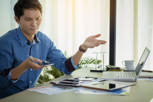 Busy businessman under stress due to excessive work. Serious focused businessman working on laptop computer online and many mobile phones.