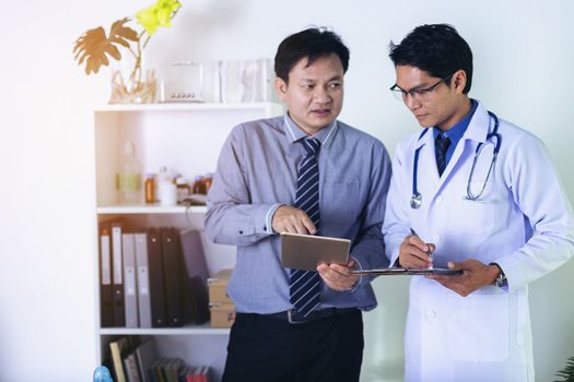 Doctor is holding a human skull in his hands and point to the skull for teaching and diagnose the symptom to the intern and medical students.