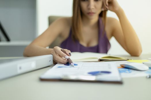 Beautiful young businesswoman working on business financial graph information .documents archive analyzing the market and considers in office and very stressful.