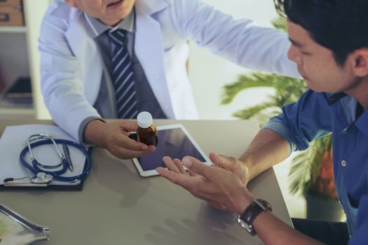 The doctor is explaining something about the medicine to the patient, in order to understand how to use it and to know the benefits and penalties of the drug.