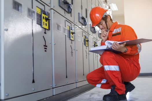 A handsome electrician is checking the electrical equipment to prepare it for use.