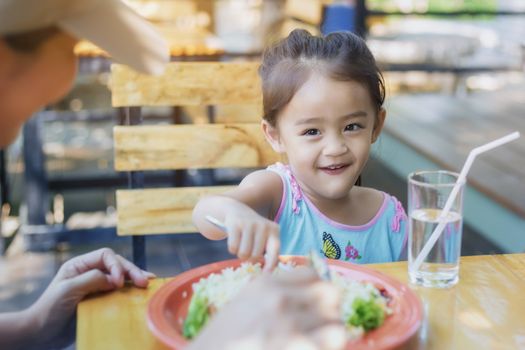 Close up Thai children eating in restaurant with her mother