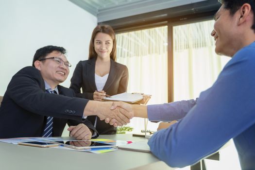 Business people handshake, businessmen hand shake, during meeting signing agreement sitting at desk team work group on conference discussing financial diagram, graph, business charts