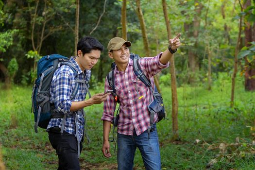 Two handsome man is touring in the woods during the holidays. Hiker walking in the forest. Autumn, nature, people concept