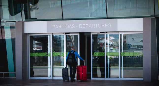 Faro, Portugal - May 3, 2018: Exterior view of Faro International Airport where passengers are walking with their suitcases on a spring day