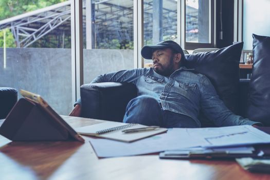 Workaholic businessman sleeping on on the sofa after a stressing job day. Feeling exhausted.  Hard work