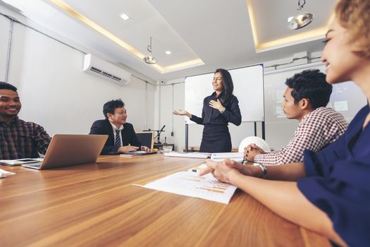 Business people are brainstorming to plan their business operations. Asian business woman leader presenting work to mixed race colleagues in the meeting