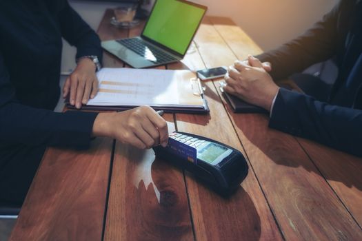 Close up of hand using credit card swiping machine to pay. Hand with creditcard swipe through terminal for payment in a restaurant. Man entering credit card code in swipe machine.