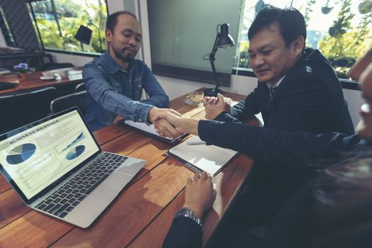 Happy smiling businessmen handshaking after signing contract meeting with businesswoman, sealing closing deal with satisfied client, bank customers come to negotiate a loan to invest.