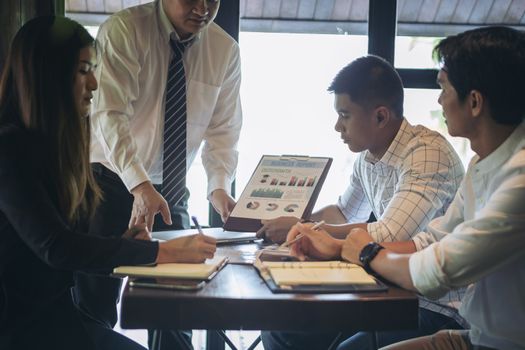 Successful businessman boss presenting new project to employees, businessman giving presentation to clients in meeting room, team leader reporting about work explaining result on flipchart. 