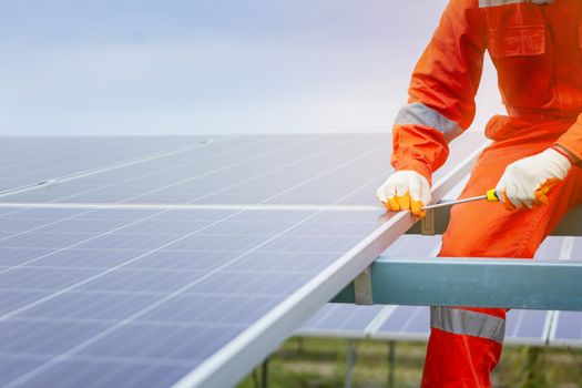 Engineers and workers in uniform and installs solid solar panels on a metal base in a solar farm.