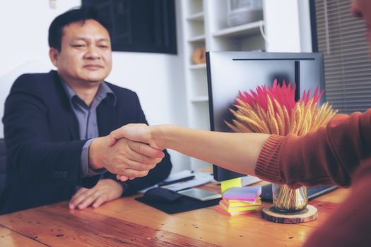 Businesspeople and partners shaking hands over the table, maintaining eye contact, confident entrepreneurs ready for effective negotiations, entering into a partnership, gender equality