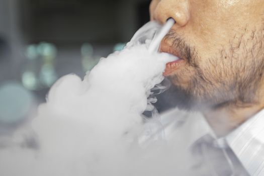 Man with a beard is smoking and throwing smoke out of his nostrils.