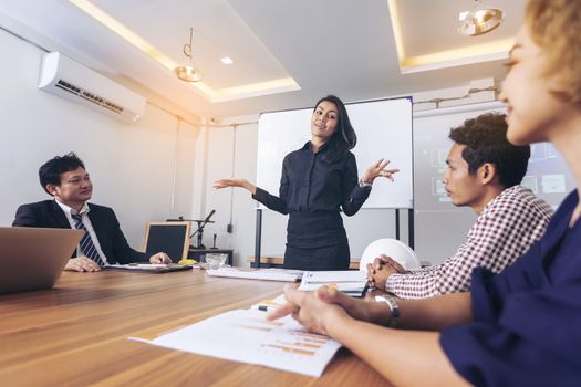 Business people are brainstorming to plan their business operations. Asian business woman leader presenting work to mixed race colleagues in the meeting