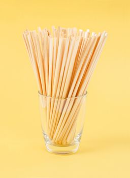 Wheat Straws for drinking water natural eco friendly renewable in glass on yellow background.