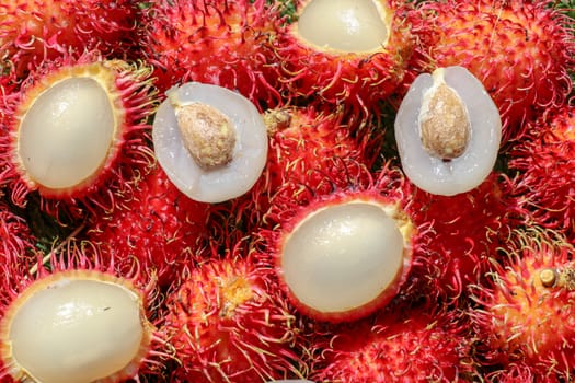 Full frame shoot of bunch of red rambutan fruits. Close up Rambutan peeled. Top view healthy fruits rambutans. The sweet fruit is a round to oval single-seeded berry covered with fleshy pliable spines