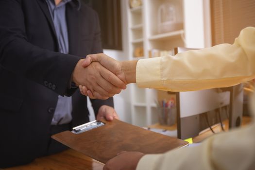 Businesspeople and partners shaking hands over the table, maintaining eye contact, confident entrepreneurs ready for effective negotiations, entering into a partnership, gender equality