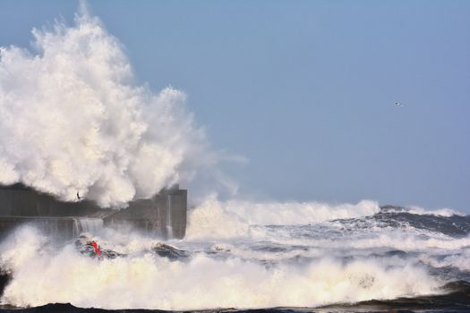 Stormy wave over lighthouse and pier of San Esteban de Pravia in Asturias, Spain.