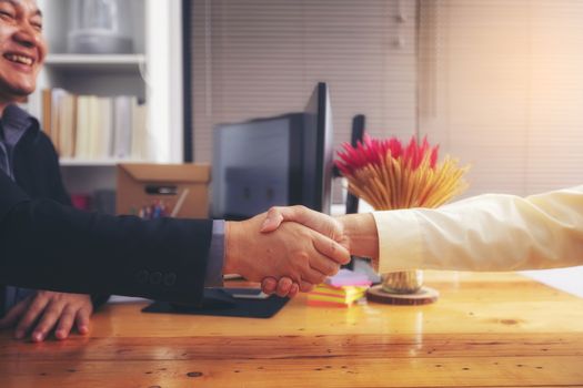 Businesspeople and partners shaking hands over the table, maintaining eye contact, confident entrepreneurs ready for effective negotiations, entering into a partnership, gender equality