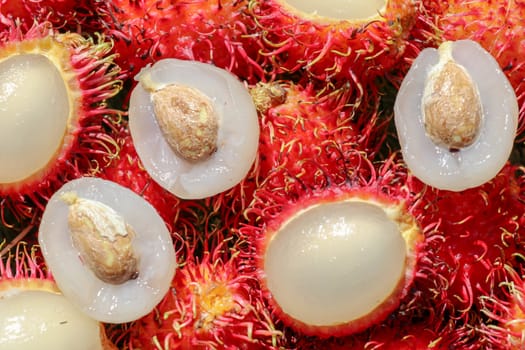 Full frame shoot of bunch of red rambutan fruits. Close up Rambutan peeled. Top view healthy fruits rambutans. The sweet fruit is a round to oval single-seeded berry covered with fleshy pliable spines