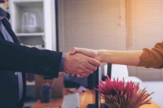 Businesspeople and partners shaking hands over the table, maintaining eye contact, confident entrepreneurs ready for effective negotiations, entering into a partnership, gender equality