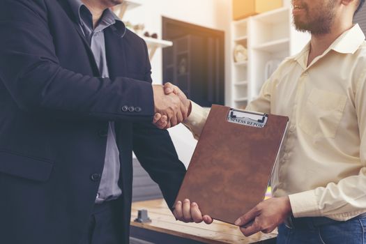 Businesspeople and partners shaking hands over the table, maintaining eye contact, confident entrepreneurs ready for effective negotiations, entering into a partnership, gender equality