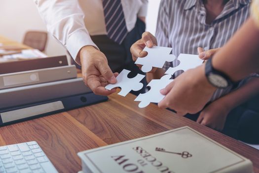 Image of a group of business people using a jigsaw puzzle to demonstrate the need to work in the same direction to work fully and effectively.