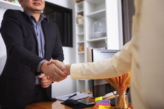 Businesspeople and partners shaking hands over the table, maintaining eye contact, confident entrepreneurs ready for effective negotiations, entering into a partnership, gender equality