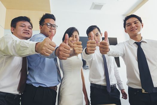 Successful business negotiators show thumbs up and smile happily.
