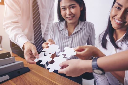 Image of a group of business people using a jigsaw puzzle to demonstrate the need to work in the same direction to work fully and effectively.