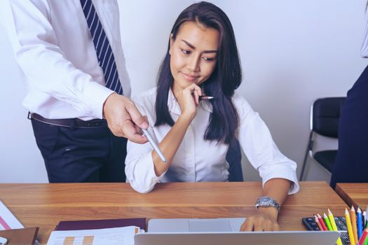 Executive mentor explaining intern or new employee  task pointing at computer screen, male boss supervisor teaching young girl to use corporate software or helping with difficult assignment