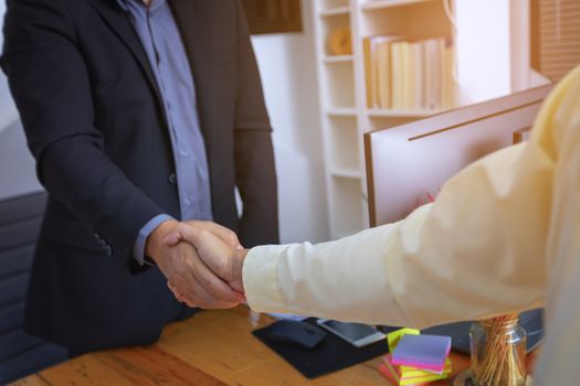 Businesspeople and partners shaking hands over the table, maintaining eye contact, confident entrepreneurs ready for effective negotiations, entering into a partnership, gender equality