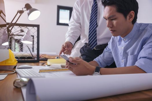 Team of architects who work on new projects and search for information from mobile.
Picture of architects working together in office