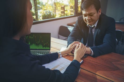 Beautiful young business man holding hands to encourage male investors unsuccessful investment. Stressed depressed business person.