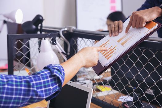 Manager holds financial report, shows rising stats and growing graphs to colleague, satisfied with great development rate, successful strategy, business growth