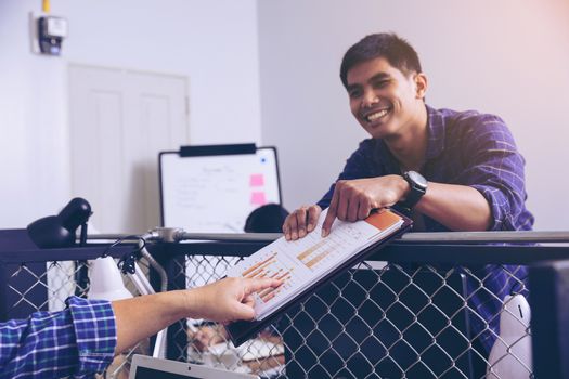 Manager holds financial report, shows rising stats and growing graphs to colleague, satisfied with great development rate, successful strategy, business growth