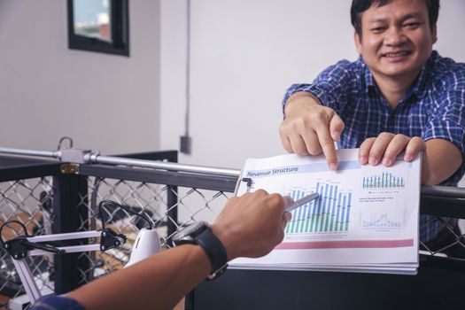 Manager holds financial report, shows rising stats and growing graphs to colleague, satisfied with great development rate, successful strategy, business growth