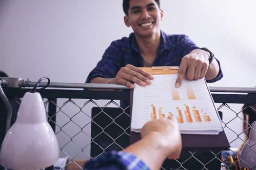 Manager holds financial report, shows rising stats and growing graphs to colleague, satisfied with great development rate, successful strategy, business growth