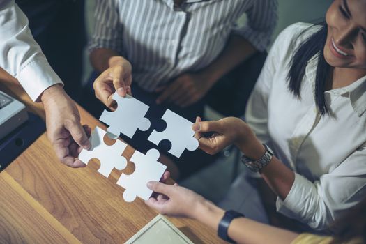 Image of a group of business people using a jigsaw puzzle to demonstrate the need to work in the same direction to work fully and effectively.