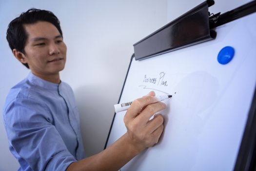 Young businessman writing on white board in conference room to planning of the agency. Business meeting presentation concept
