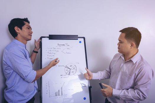 Young businessman writing on white board in conference room to planning of the agency. Business meeting presentation concept
