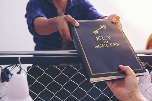 Senior businessman deliver the book about the keys to business success to the next generation business.