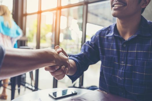 Businessmen negotiate in a coffee shop. Hold hands and greet before the business talks comfortably.