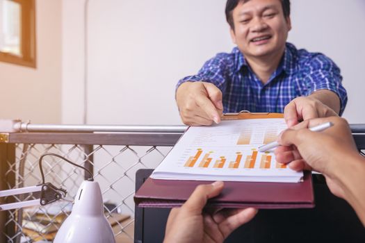 Manager holds financial report, shows rising stats and growing graphs to colleague, satisfied with great development rate, successful strategy, business growth